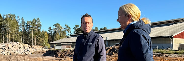 Två personer pratar utomhus, blå himmel, tallskog, sten